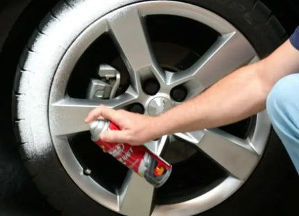 a man is using a spray to clean the rim of a car